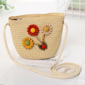 Detailed shot of beige straw crossbody bag for kids with sunflower and ladybug decor