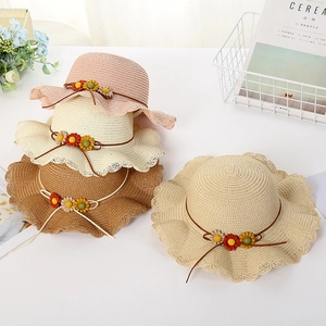 Detail of woven straw hats for kids with scalloped edges and colorful floral embroidery