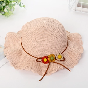 Detail of pink straw sun hat with woven wavy brim and colorful daisy flower ornaments