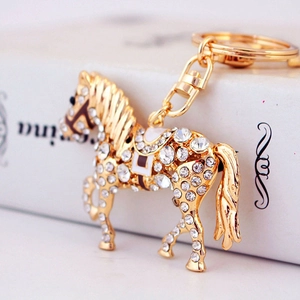 Porte-clés cheval doré orné de cristaux brillants et d'une selle en émail blanc