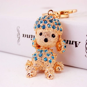 Golden poodle keychain with blue rhinestones on a white background with books