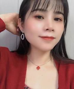 Detail showing red clover necklace and silver teardrop earrings on a model person