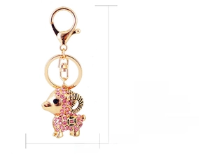 Macro detail of gold plated goat keychain with pink crystals and dimension markings
