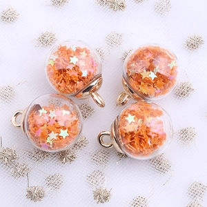 Macro detail of four orange star sequin glass globe charms with golden metal loops