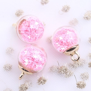 Detail of pink star sequins inside a glass globe charm with a gold metal loop