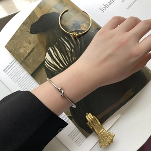 Detail of minimalist knot cuff bracelets in gold and silver finish worn on a wrist