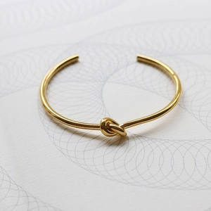 Detailed view of the 18K gold plated knot cuff bracelet with polished metallic finish