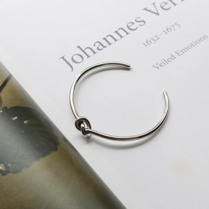 Macro detail of silver knot cuff bracelet showing the polished metal finish and open design