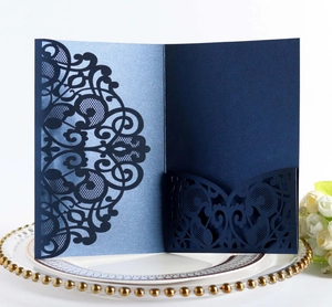 Detail of laser-cut navy blue invitation card with lace patterns on a decorative plate