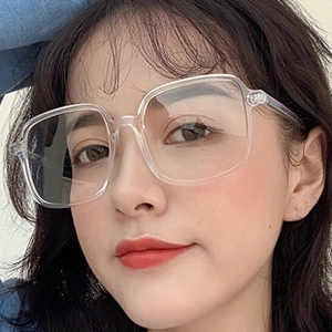 Close-up of a model wearing large transparent square glasses with retro metal frames