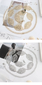 Close-up of hollow leaf metal waist chains in gold and silver on a marble surface