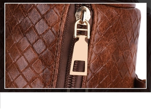 Macro shot of brown woven leather texture and gold metal zipper on the shoulder bag