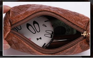 Close-up of brown woven leather makeup pouch showing internal storage capacity and mirror