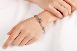 Silver chain bracelet with love heart and bear charms shown on a model's wrist