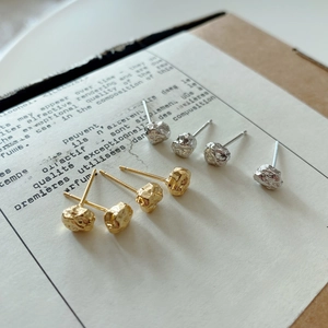 Detailed close-up of irregular textured lava silver studs in gold and silver finish