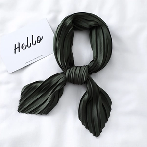 Detail of dark green pleated silk scarf showing elegant folds and satin texture