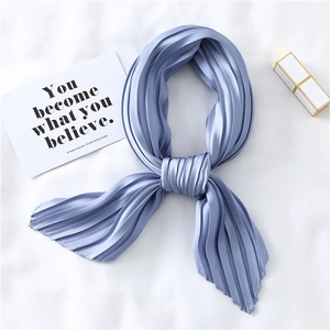 Pleated sky blue faux silk scarf with a knotted design on a minimalist white background