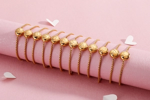 Detailed view of adjustable gold zodiac bracelets displayed on pink pillars with heart decor