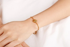 Close-up of a minimalist gold zodiac bracelet with a sparkling diamond pendant on wrist