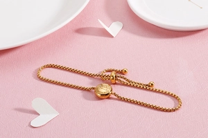 Detail of adjustable gold Sagittarius bracelet with sparkling stones on pink background