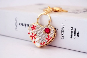 Macro view of crystal heart keychain with red gemstone and floral pattern on white background
