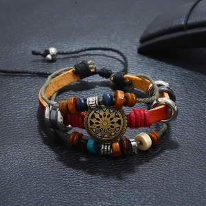 Macro detail of multilayer vintage leather bracelet with bronze sun pendant and wooden beads