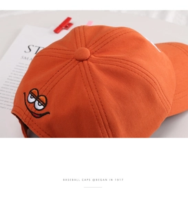 Close-up of a vibrant orange cotton baseball cap with a unique cartoon embroidery design