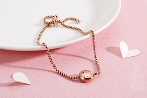 Detail of rose gold Cancer zodiac bracelet with adjustable sliding clasp on a white plate
