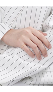 Detail shot of a minimalist gold open ring with a single zircon on a hand