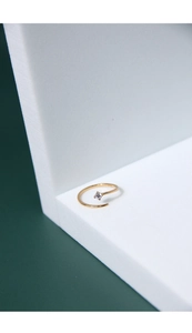 Detail shot of a gold shooting star open ring with a single zircon on a green backdrop