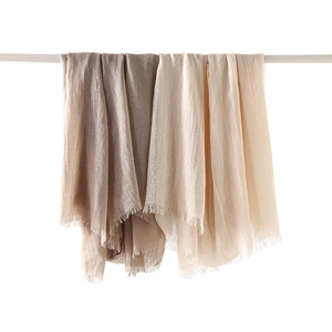 Linen cotton scarves in gradient earthy tones with elegant fringe edges hanging on a rod