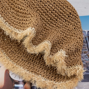 Handcrafted crochet straw sun hat with raw fringe edges in natural brown for beach
