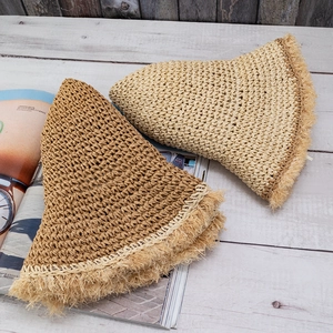 Detailed close-up of straw hats showing fringed edges in light beige and camel colors