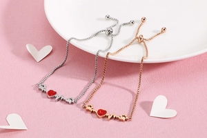 Detail of adjustable heart bracelets with red stone heartbeat line in silver and rose gold