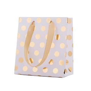 White paper gift bag with gold polka dots and matching golden ribbon handles