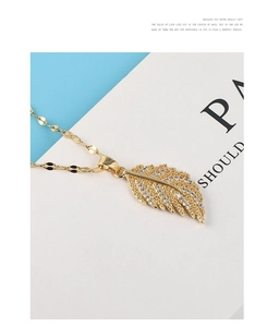 Macro detail of 18K gold plated feather pendant with sparkling pavé cubic zirconia