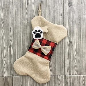 Detail of bone-shaped burlap Christmas stocking with red plaid cuff and lace bow decoration