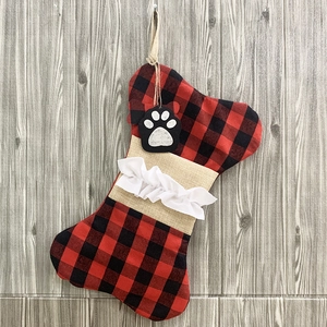 Detail of bone-shaped Christmas stocking with red black plaid and paw print tag