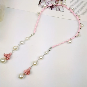 Detailed macro view of pink braided cord mask chain with pearls and tassel accents
