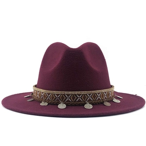 Detail of burgundy wool fedora hat featuring ethnic ribbon and silver coin charms