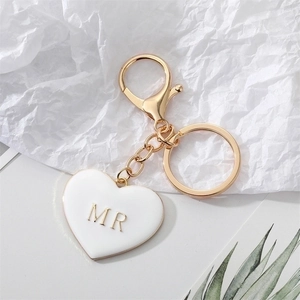 Gold keychain featuring a white heart pendant with golden MR letter on wrinkled paper