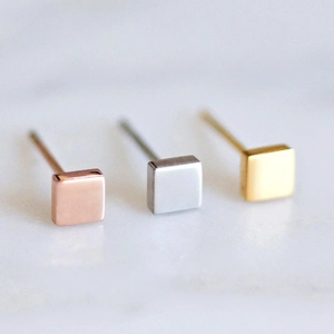 Macro view of minimalist square stud earrings in rose gold, silver, and gold finishes