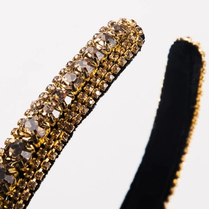 Macro shot of luxury gold rhinestones on a vintage baroque style black velvet headband