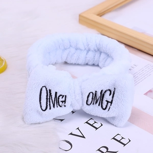 Light blue coral fleece headband with OMG embroidery and bow for skincare and makeup