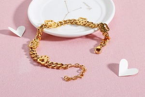 Detailansicht eines goldenen Edelstahl-Armbands mit hohlen Haustierpfoten-Anhängern