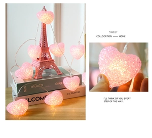 Close-up of pink heart-shaped crystal LED lights on an Eiffel Tower model and books