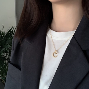 Detail of S925 silver crescent moon necklace with pearl on model's neck with blazer