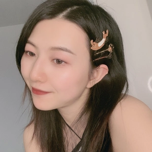 Close-up of a cute cat-shaped brown hair clip worn by a model against a white wall