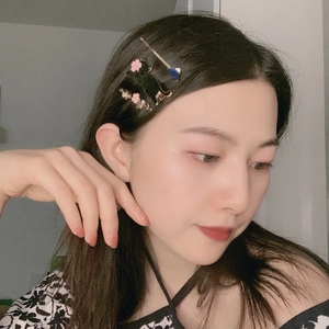 Detailed view of a black cat hair clip with pink flowers worn by a model in soft light