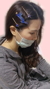Detail of star and cat hair clips in blue enamel on model hair with golden clips